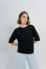 Buzo de tejido abierto color beige claro, de calce oversize con mangas 3/4 y cuello redondo. Presenta terminaciones acanaladas en puños y cintura.