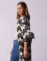 Cardigan largo de crochet color crudo con diseño de ondas en negro.