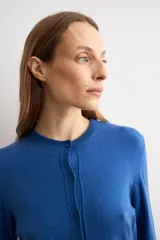 Cardigan de punto azul con cuello redondo, manga larga y cierre frontal abotonado con pequeños botones al tono.