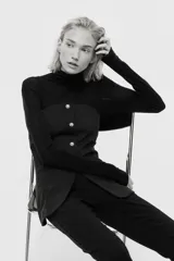 Top strapless entallado confeccionado en punto roma, con cierre frontal de botones decorativos tipo joya y corte ligeramente acampanado en la parte inferior.