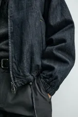 Cazadora de corte relajado confeccionada en tejido denim de algodón sin lavados, con ligero acolchado interior. Presenta cuello solapa en tejido efecto piel a contraste, cierre frontal de cremallera, bolsillos de vivo en la cadera y puños elásticos.