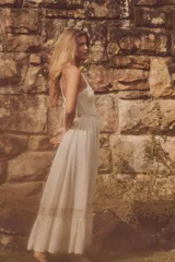 Vestido midi color crudo, con breteles anchos y escote recto. La parte superior es de tejido de punto calado y la falda es lisa con volado y detalle de puntilla en el ruedo. Tiene abertura en la espalda y cintura elastizada.