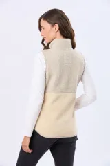 Chaleco de sherpa combinado en tonos beige, con cuello alto y cierre frontal. Presenta una textura suave y abrigada, ideal para capas adicionales.