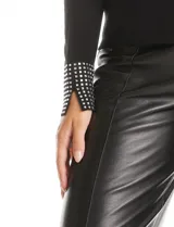 Polera de tejido soft color negro, con cuello alto y puños decorados con apliques de strass. Presenta un diseño de manga larga y corte ajustado.
