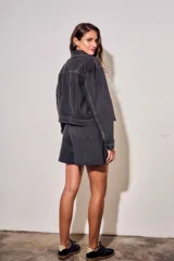 Campera oversize de denim negro, con cuello camisero, cierre frontal con botones y bolsillos ojal.