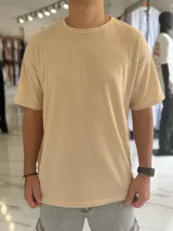 Remera oversize de tejido de punto color beige, de manga corta y cuello redondo.
