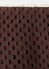 Falda corta de tejido crochet color marrón con detalles de flores blancas en el borde inferior. Silueta recta y forro interior.