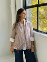 Sweater de punto rosa claro con diseño de capas, que incluye una camisa blanca debajo y un pañuelo a juego con detalles de encaje y flecos en el ruedo.