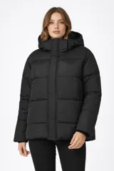 Campera puffer negra con diseño capitoneado, cierre frontal con solapa, capucha integrada y forro interior de corderito.