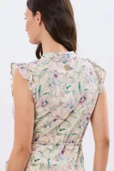 Vestido corto de lino estampado con diseño floral en tonos lila y verde, sin mangas, con cuello mao, botones frontales, volados en los hombros y detalle de lazo en la cintura.