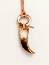 Collar con dije de resina en forma de colmillo con efecto carey en tonos marrones y blancos, sujeto por una tira de gamuza marrón y un anillo superior de resina a juego.