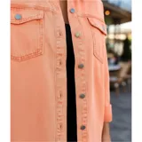 Campera tipo sobrecamisa de jean en color naranja, con corte oversize, cuello italiano, cierre frontal con botones metálicos y ruedo deshilachado. Cuenta con bolsillos frontales con solapa y mangas largas.