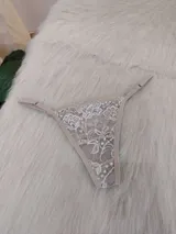 Microtanga de encaje con diseño floral, breteles finos regulables y terminaciones en color tostado.