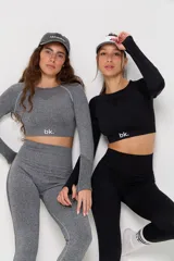 Conjunto deportivo de dos piezas compuesto por un top de manga larga con abertura en la espalda y calzas de tiro alto con diseño de contorno moldeador. Ambas prendas presentan un acabado jaspeado y detalles de tejido técnico con textura.