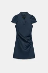 Vestido corto de denim azul con cuello mao, cierre tipo alamar en el pecho, mangas cortas abullonadas y fruncido lateral.