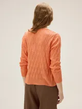 Buzo de tejido en lurex con escote en V, manga larga y silueta relajada, con un brillo sutil y textura tramada.