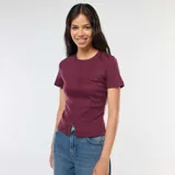 Remera de punto de canalé color borgoña, de corte ajustado, con cuello redondo y mangas cortas. Presenta una costura vertical central en el frente y una pequeña abertura en el ruedo.