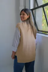 Chaleco de punto color beige, con cuello en V y diseño de trenzas verticales. Presenta un corte holgado y terminaciones acanaladas en el cuello, sisas y ruedo.