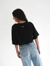 Top corto azul marino de punto, con mangas cortas amplias, cuello redondo y detalle de escudo bordado en la parte delantera.