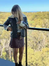 Campera de cuero de oveja italiano con diseño slouchy, cuello de piel sintética desmontable y detalles de piel en puños y bolsillos. Presenta cierre frontal con botones a presión.