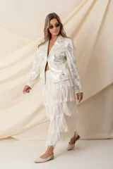 Pollera midi color vainilla, de gasa plisada con flecos y cintura elastizada.