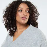 Sweater de punto gris con cuello en V, mangas largas y puños acanalados.