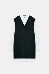 Vestido corto que combina una camisa blanca de manga larga con cuello solapa y botones frontales, con un chaleco de tejido negro de punto con escote en V.