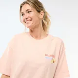 Camiseta oversize de color rosado con cuello redondo y mangas cortas. En la espalda presenta un estampado gráfico que incluye la leyenda "DELIZIOSO SICILIA", rayas verticales y frutas cítricas con hojas.