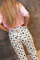 Pantalón de jean de corte recto con estampado integral de caballos, estrellas y motivos geométricos. Presenta aberturas en el ruedo y cierre frontal con botón.