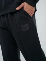 Pantalón jogger celeste de felpa, con cintura elástica ajustable con cordón, puños elastizados en los tobillos y un parche con el logo de la marca en la pierna izquierda.