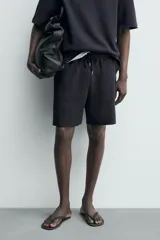 Bermuda estilo jogger de ajuste relajado, color negro, confeccionada en tejido interlock de algodón. Cuenta con cintura elástica ajustable mediante cordón, bolsillos delanteros tipo vivo y diseño liso.