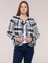Chaqueta de tweed en blanco y negro con patrón de cuadros, escote redondo, bolsillos frontales con botones metálicos y flecos decorativos en los bordes y puños.