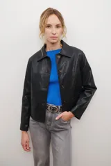 Chaqueta corta color beige con cuello de piel sintética negra, cierre frontal de botones y bolsillos laterales.