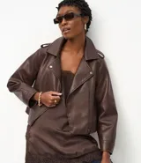 Campera estilo biker de cuero sintético color marrón chocolate, con cuello solapa, cierre asimétrico, bolsillos laterales con cremallera y detalles de botones metálicos. Incluye hombreras decorativas y puños estructurados.