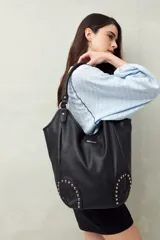Bolso shopper negro de símil cuero texturizado con asas de hombro y detalles de tachas metálicas.