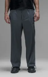 Pantalón de corte oversize color gris carbón, confeccionado en microfibra técnica. Presenta cintura elástica, bolsillos laterales, un bolsillo cargo con cierre de broche y sistema de elásticos con tancas en los tobillos para regular la apertura.
