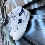 Championes de corte alto New Balance modelo 650, con diseño inspirado en el básquetbol. Presentan una combinación de cuero blanco y detalles en azul marino, con puntera de gamuza gris claro y suela de goma en tonos grises.