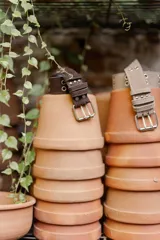 Cinto ancho negro de estilo gótico o punk, con doble hebilla metálica plateada y múltiples ojales metálicos a lo largo de la tira.