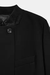 Blazer corta negra ZARA Woman Collection, con cuello subido combinado, manga larga, bolsillo ojal en el pecho y cierre frontal cruzado con botón.