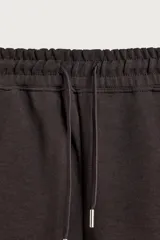 Bermuda estilo jogger de ajuste relajado, color negro, confeccionada en tejido interlock de algodón. Cuenta con cintura elástica ajustable mediante cordón, bolsillos delanteros tipo vivo y diseño liso.