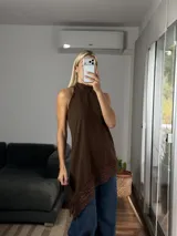 Musculosa de cuello alto con diseño irregular y bajo asimétrico, confeccionada en tela tipo cey con detalle de puntilla en el ruedo.