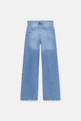 Jeans de tiro alto con corte wide leg y largo completo. Presenta diseño de cinco bolsillos, trabillas en la cintura y cierre frontal con cremallera y botón, con un acabado de efecto lavado.