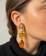 Caravanas colgantes de resina color mostaza, compuestas por piezas geométricas en degradé que culminan en un dije en forma de gota.
