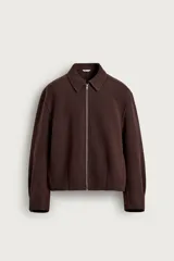 Cazadora de corte boxy fit color marrón, confeccionada en tejido con mezcla de lana. Presenta cuello solapa, manga larga, bolsillos de vivo en la cadera y cierre frontal de cremallera metálica.