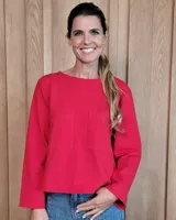 Remera de manga larga color rojo, con cuello redondo y dos bolsillos frontales tipo parche. Presenta un corte recto y holgado.