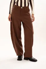 Pantalon de tiro medio con silueta curvada, mas ancha en la zona del muslo y la rodilla, con bolsillos laterales y cierre frontal con cremallera y boton.