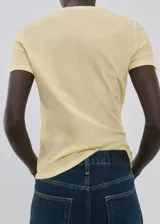 Remera de algodón color amarillo claro, con cuello redondo, manga corta y costuras pespunteadas a la vista en el frente y sisas.