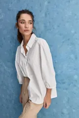 Camisa blanca de algodón, de calce relajado, con cuello camisero, frente abotonado y mangas largas abullonadas.