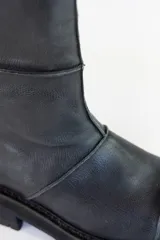 Bota de caña media color negro, de cuero, con suela track y cierre lateral.