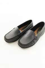 Mocasines de cuero vacuno color beige con acabado mate, costuras visibles artesanales en el empeine y suela de perfil bajo.